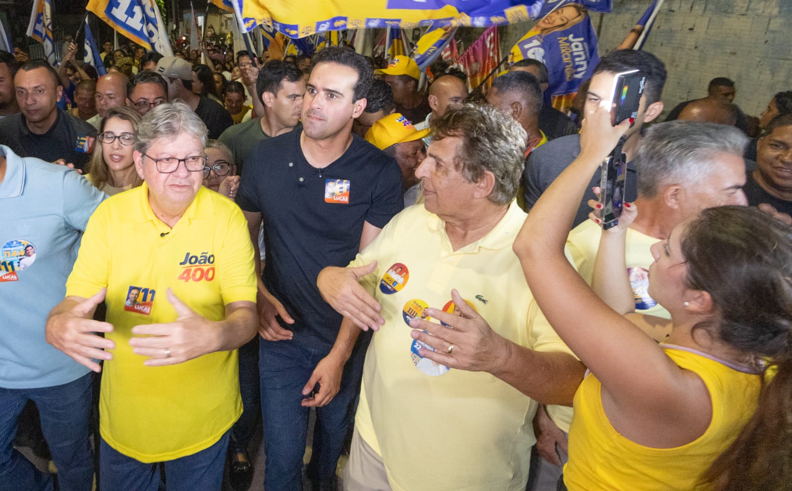 João Azevêdo, Lucas Ribeiro e Domiciano Cabral, caminham cercados por militantes e lideranças políticas segurando bandeiras