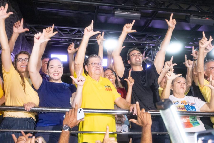 Lucas Ribeiro, João Azevêdo e apoiadores comemoram em cima de veículo com mãos levantadas fazendo gesto de campanha
