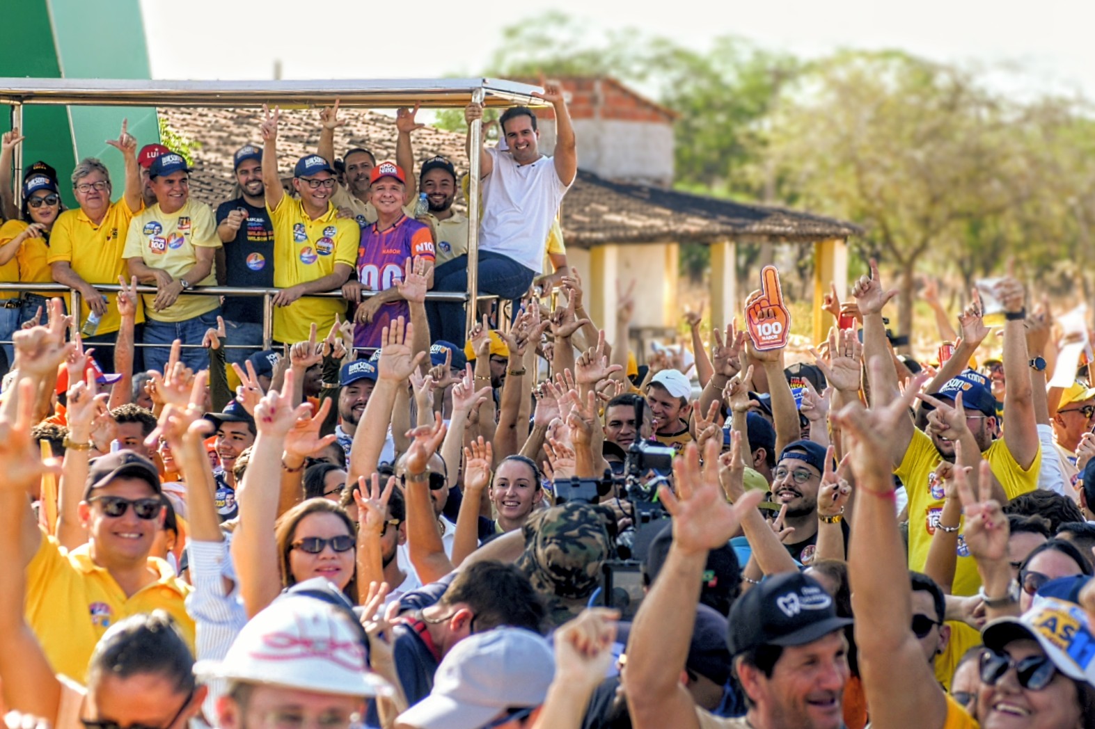 Lucas Ribeiro, João Azevêdo e comitiva acenam em cima de veículo cercados por dezenas de apoiadores com braços erguidos.