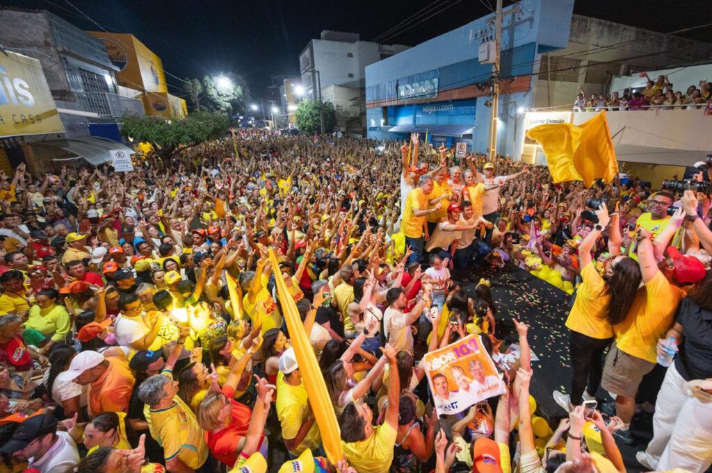 Imagem aérea em ângulo aberto mostra avenida de Sousa completamente lotada por apoiadores vestidos de amarelo acompanhando a comitiva sobre o palco.