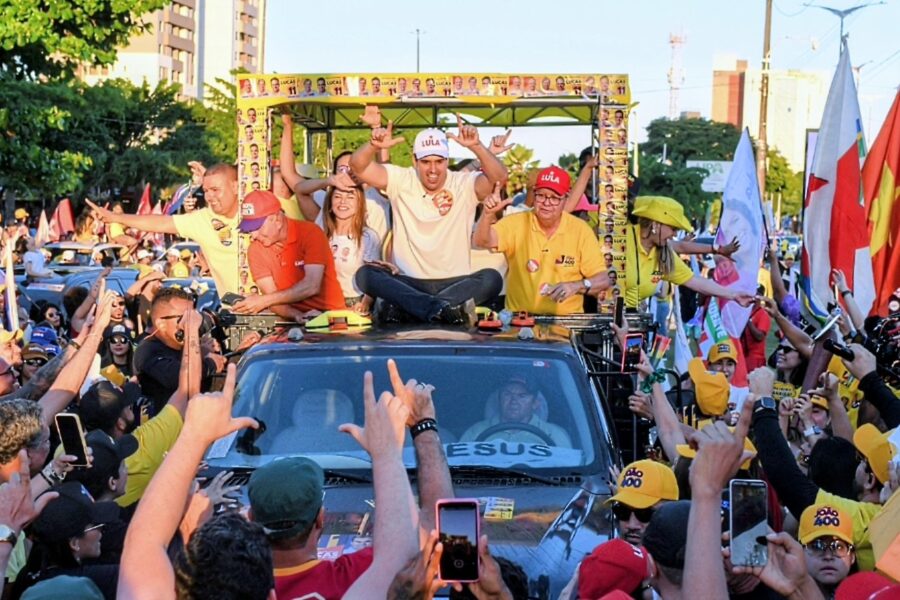 Multidão faz sinal de vitória e campanha com as mãos em direção a João Azevêdo e Lucas Ribeiro sobre o veículo.